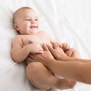 Colics prevention. Masseur massaging tummy of newborn baby, healthcare and babycare, copy space